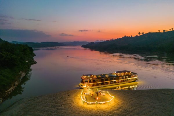 Aerial of lanterns and BBQ dinner for guests of boutique river cruise ship Mekong Star (Lernidee Erlebnisreisen) moored along sandbar on Upper Mekong river at sunset, Mad, Vientiane Province, Laos